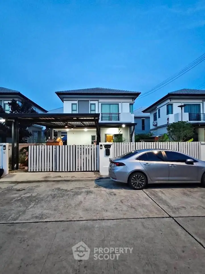 Modern two-story house with sleek design and car parked in driveway at dusk.