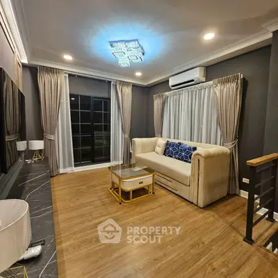 Elegant living room with modern decor, featuring a plush sofa, stylish lighting, and large windows with drapes.