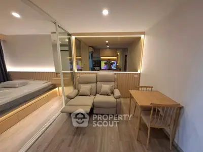 Modern studio apartment with cozy seating and dining area, featuring elegant lighting and mirrored wall.