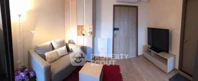 Cozy modern living room with stylish furniture and flat-screen TV, perfect for relaxation.
