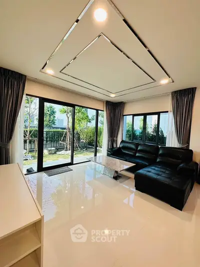 Luxurious living room with modern black leather sofa and large windows offering garden views.