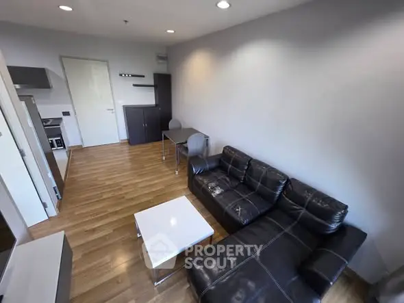 Modern living room with sleek black leather sofa and wooden flooring