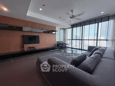 Spacious modern living room with large windows and city view, featuring sleek furniture and stylish decor.