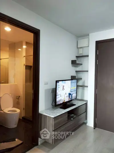 Modern apartment interior with sleek TV unit and adjacent bathroom, showcasing contemporary design and functionality.