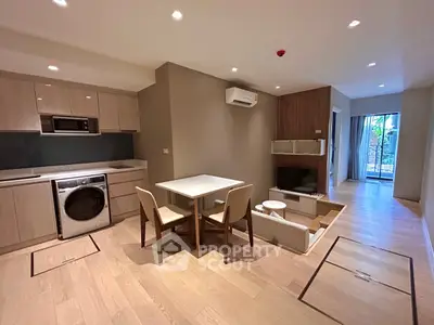 Modern open-plan living room with kitchen and dining area, featuring sleek appliances and stylish decor.