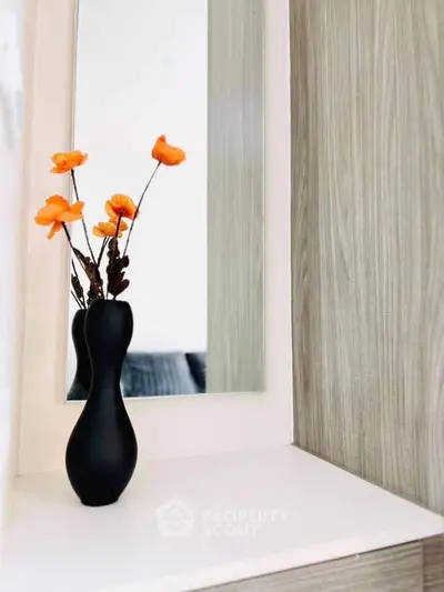Elegant interior decor with a stylish vase and flowers on a modern shelf.