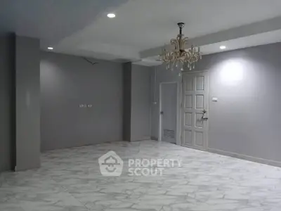 Spacious empty room with elegant chandelier and marble flooring