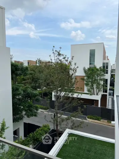 Modern residential neighborhood with contemporary white buildings and lush greenery.