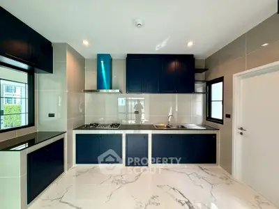 Modern kitchen with sleek cabinetry and marble flooring, featuring a gas stove and ample natural light.