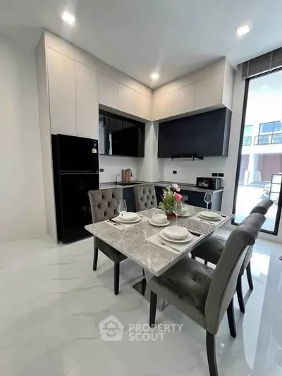 Modern kitchen with sleek design, featuring dining table and large window for natural light.