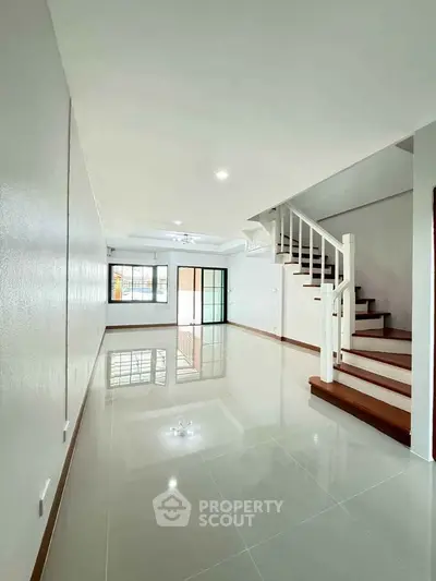 Spacious modern living room with glossy floors and elegant staircase