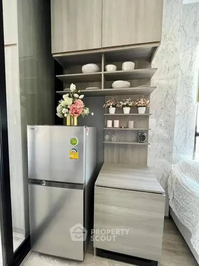 Modern kitchen with sleek fridge and stylish cabinetry in compact apartment.