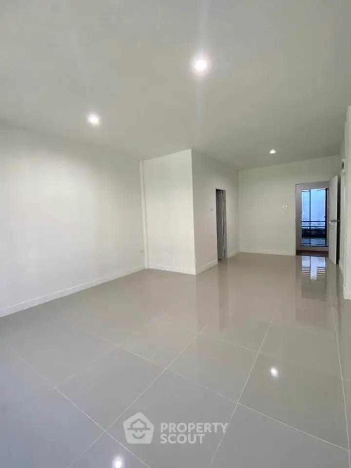 Spacious modern living room with glossy tiled floors and bright lighting.