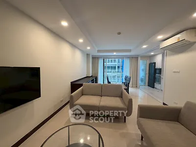 Modern living room with sleek furniture and open kitchen layout in a high-rise apartment.