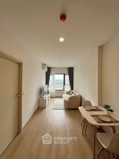 Modern living room with cozy seating and dining area, featuring a large window with a view.