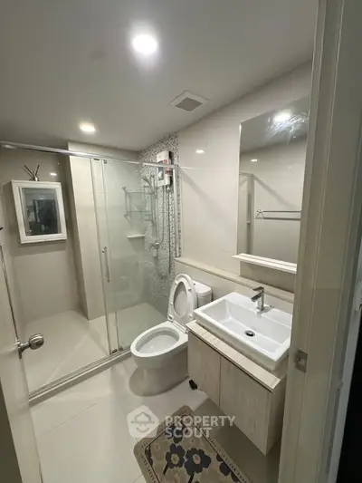 Modern bathroom with glass shower and sleek fixtures in contemporary apartment.