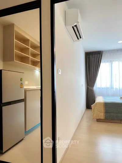 Modern apartment interior with kitchen and bedroom, featuring sleek design and natural light.