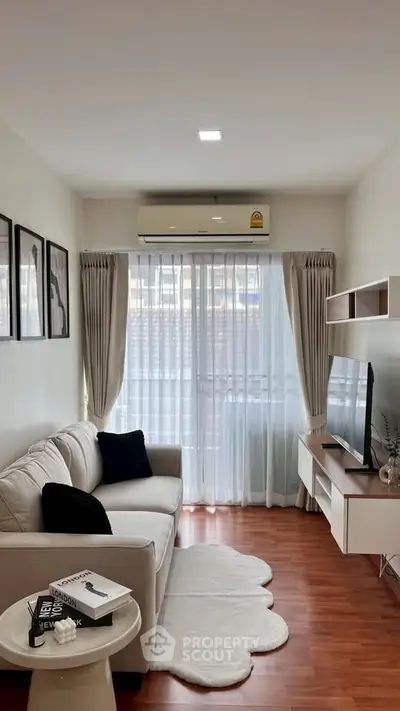 Cozy living room with modern decor and large window, featuring a comfortable sofa and wall-mounted TV.