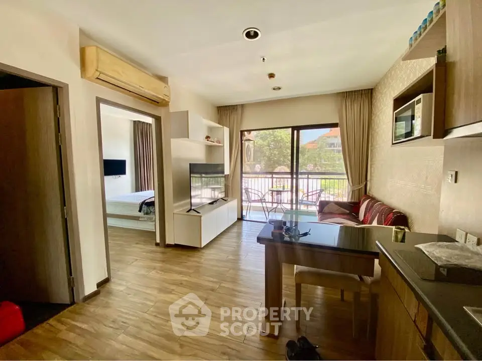Modern open-plan living room with balcony access and stylish kitchen in a cozy apartment.