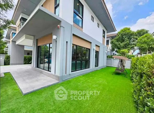 Modern two-story house with lush green lawn and large windows, perfect for family living.