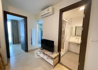 Modern apartment interior with TV, air conditioning, and bathroom access.