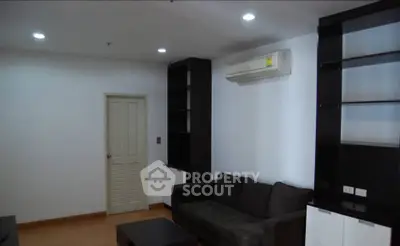 Modern living room with sleek black furniture and built-in shelves, featuring a minimalist design.