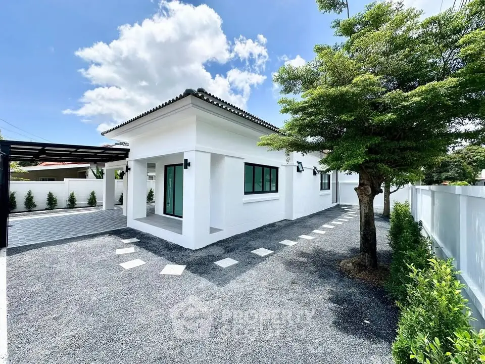 Charming modern white house with spacious driveway and lush greenery, perfect for serene living.