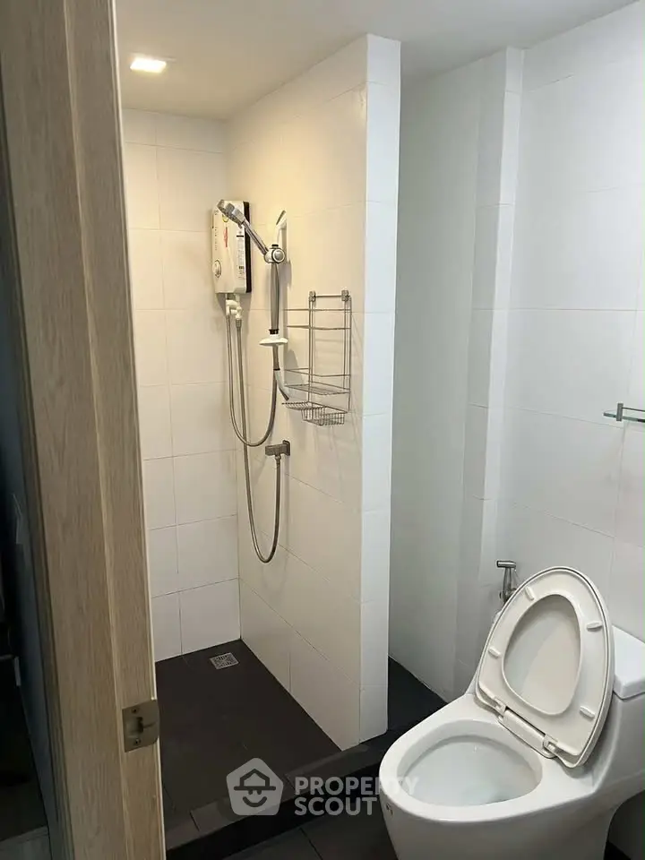 Modern bathroom with shower and toilet in sleek white tile design.