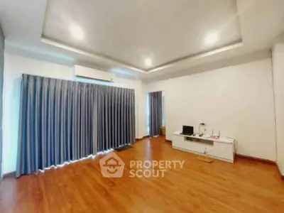 Spacious empty living room with wooden flooring and modern ceiling lights.