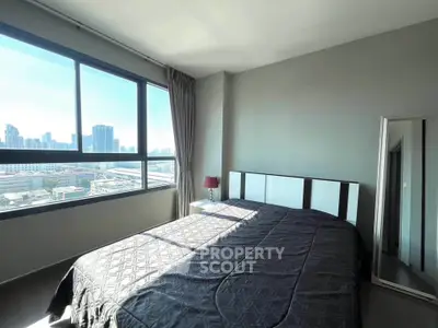 Spacious bedroom with large window offering stunning city views in modern apartment.