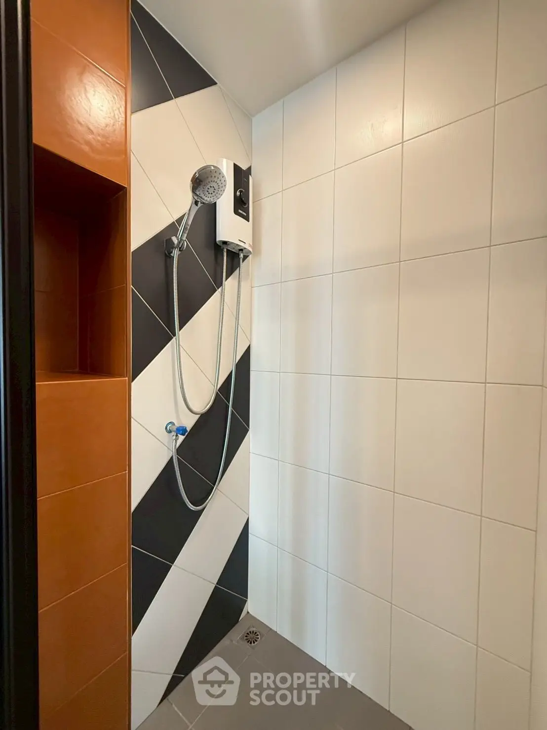 Modern bathroom shower with stylish geometric tile design and built-in shelving.