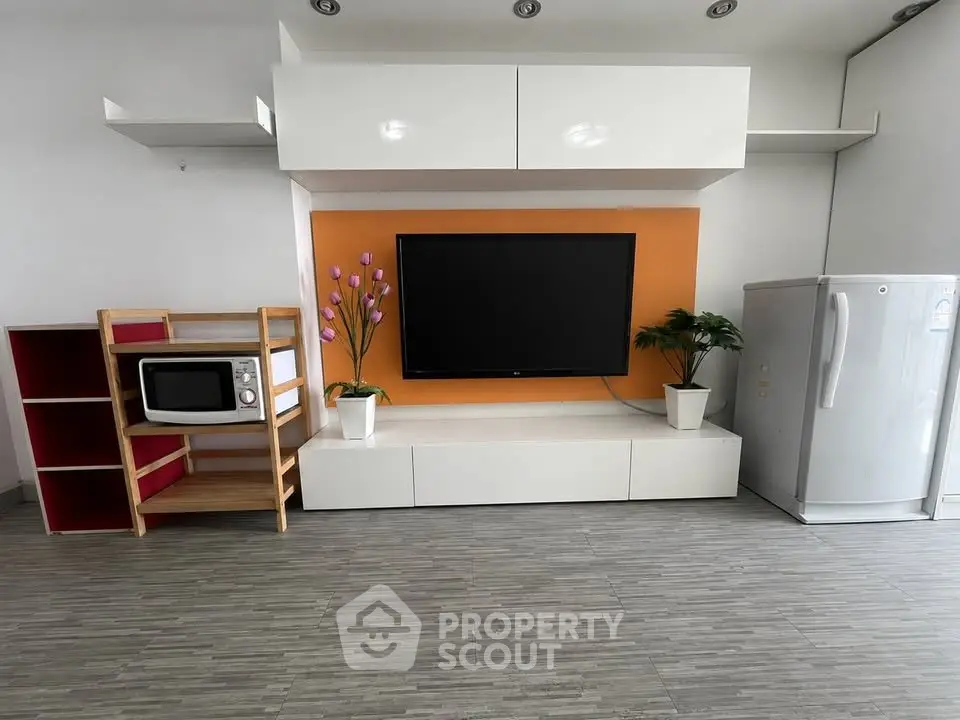Modern living room with sleek TV setup, stylish shelving, and contemporary appliances.