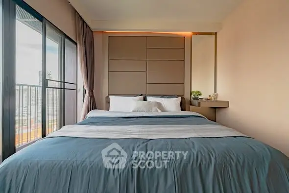 Modern bedroom with large window and stylish decor in urban apartment.