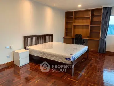 Spacious bedroom with wooden flooring and built-in shelves, perfect for comfort and organization.