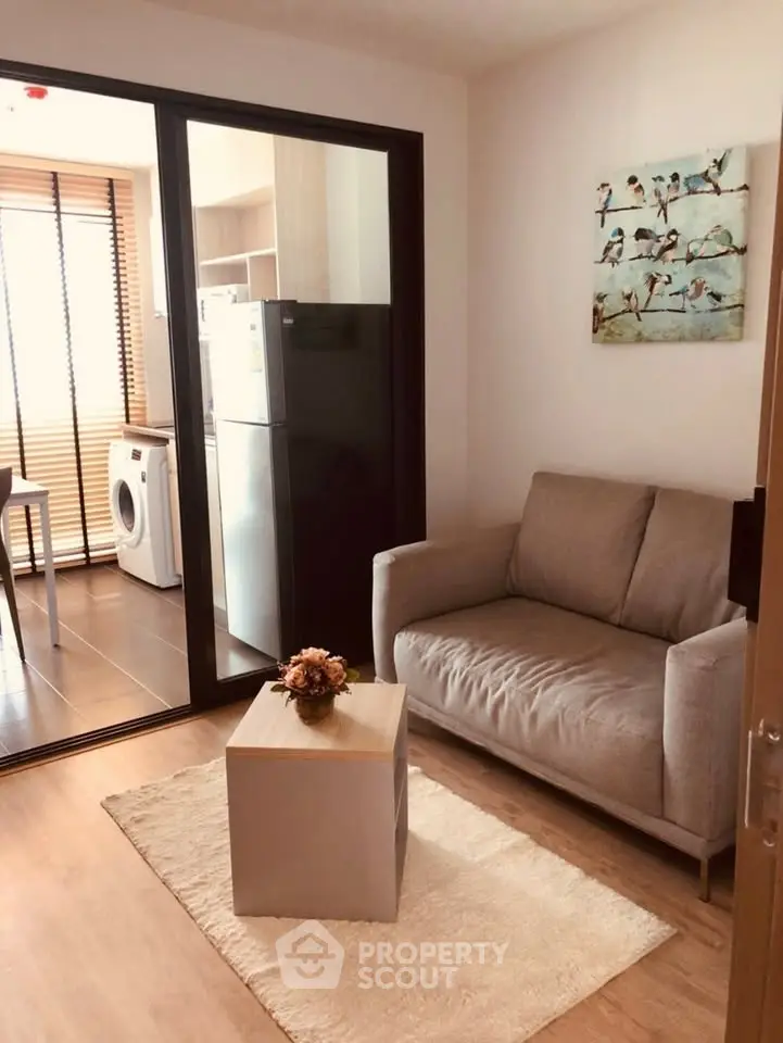 Cozy living room with modern decor and adjacent laundry area in a stylish apartment.