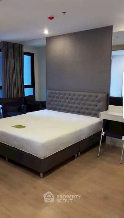 Spacious modern bedroom with elegant decor and large windows for natural light.