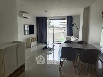 Modern living room with sleek furniture and large window offering natural light.