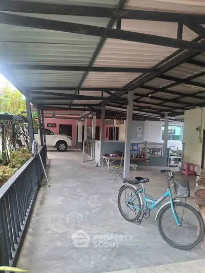 Spacious covered patio with bicycle and car, ideal for outdoor activities.