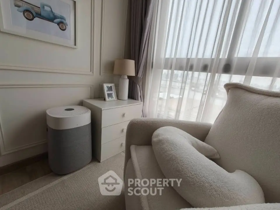 Cozy living room with plush armchair, stylish decor, and natural light through sheer curtains.