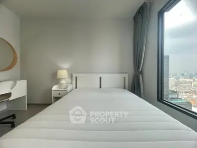 Modern bedroom with city view, featuring a cozy bed, stylish desk, and large window for natural light.