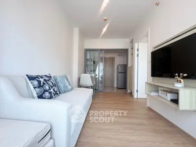 Modern living room with sleek design, featuring a cozy sofa, wall-mounted TV, and open kitchen layout.
