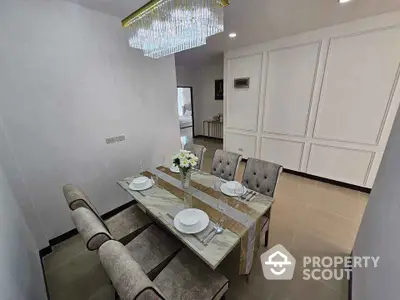 Elegant dining area with modern chandelier and stylish table setting in a contemporary home.