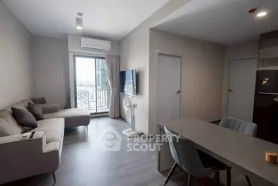 Modern living room with balcony view, sleek furniture, and open dining area in a stylish apartment.