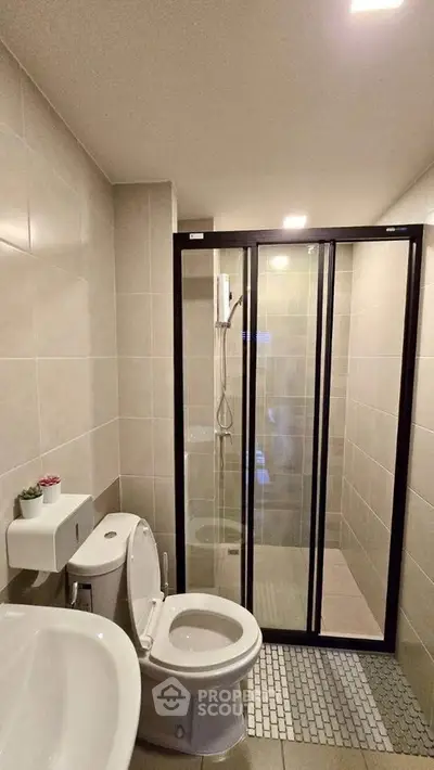 Modern bathroom with glass shower enclosure and sleek fixtures.