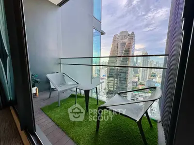 Modern balcony with city view, featuring sleek chairs and artificial grass flooring.