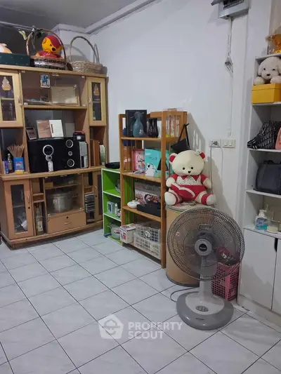 Cozy living room with tiled floor, wooden shelves, and decorative items for a homely feel.