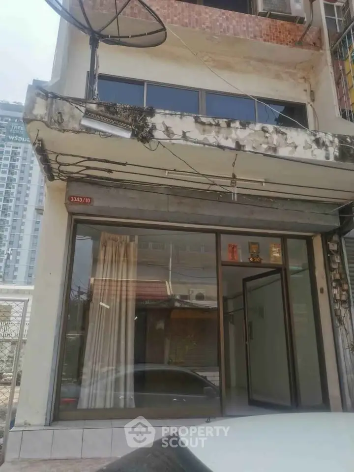 Charming urban building facade with large windows and balcony, ideal for renovation or investment opportunity.