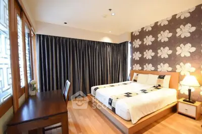 Spacious bedroom with elegant floral wallpaper and wooden flooring.