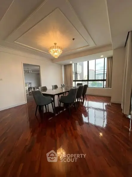 Elegant dining room with polished wooden floors and a stunning chandelier, offering a sophisticated ambiance.