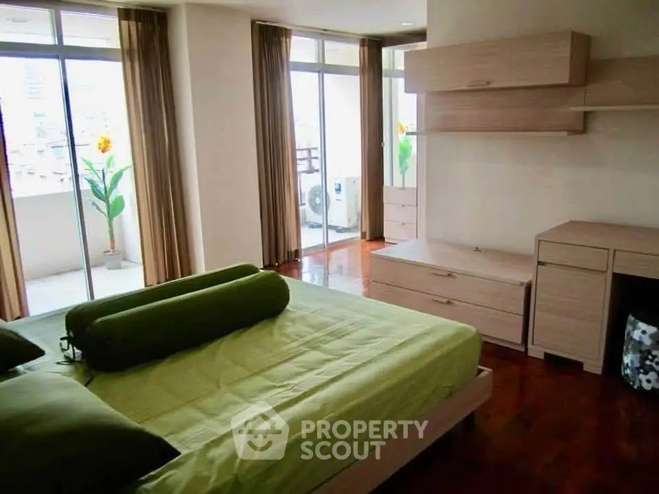 Spacious bedroom with balcony access and modern furnishings in a bright apartment.